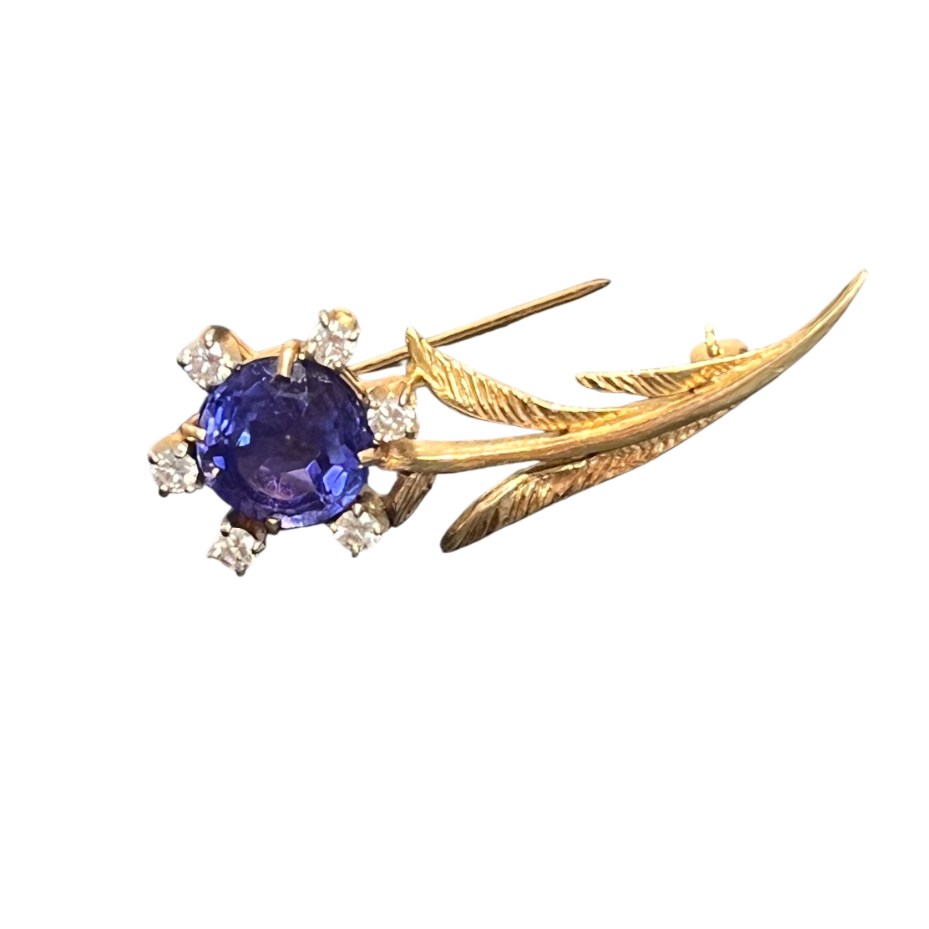 Gold brooch with a blue gemstone on a white background
