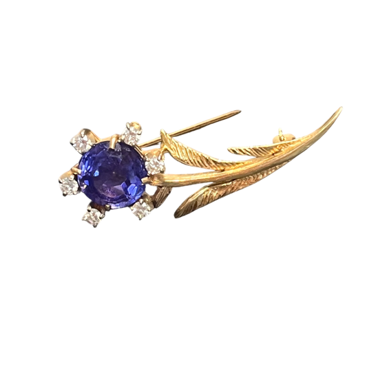 Gold brooch with a blue gemstone on a white background